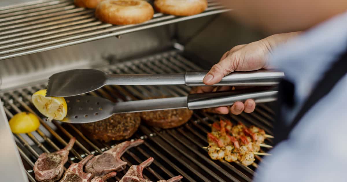 man grilling hamburger on an open grill